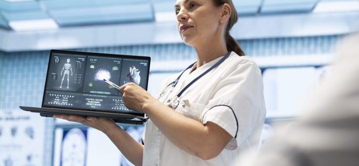 In a treatment center, medical experts team discuss patient care strategies. Licensed doctor pointing at heart and brain radiography scans on laptop, neurology and cardiology analysis.